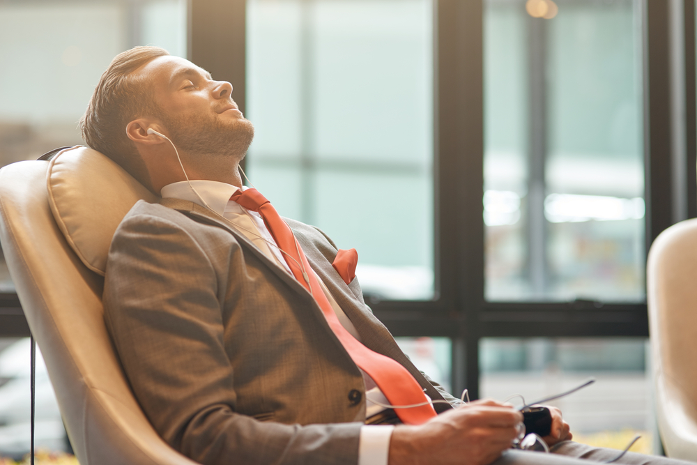 young businessman having a nap and listening to music while resting in the departure lounge